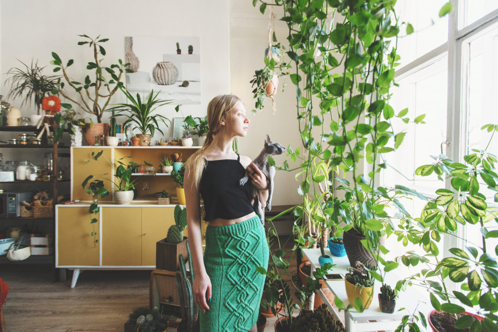 female holding pet with vines and hanging plants inside the house