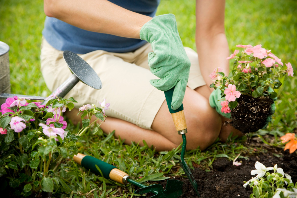 woman planting flowers in the soil with gloves