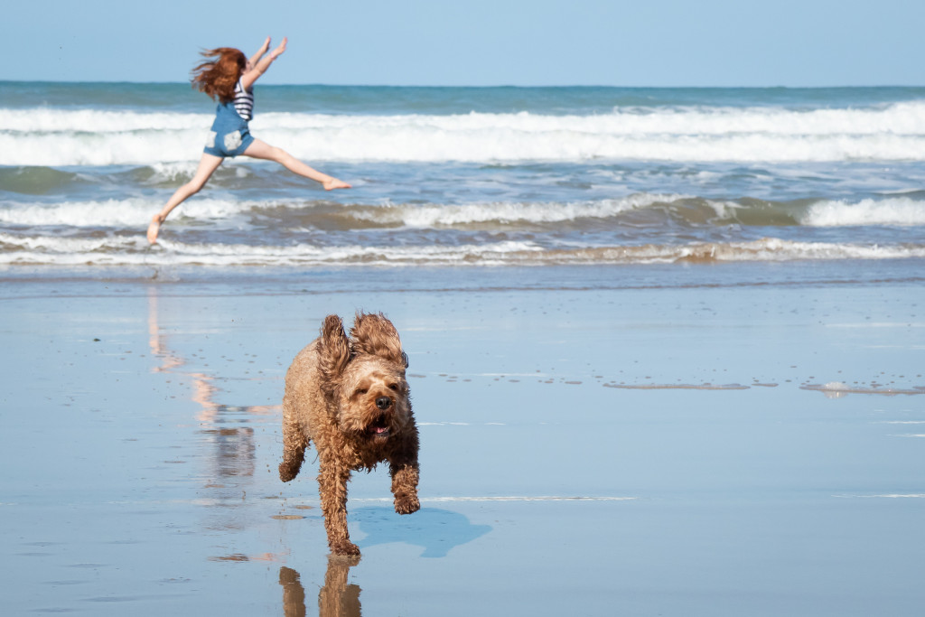 A girl and a dog running on a beach